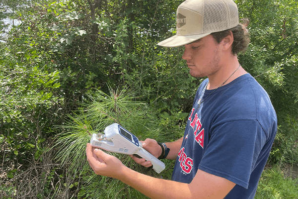 Sam Williamson using the LI-600N to take stomatal conductance and fluorescence measurements outdoors.
